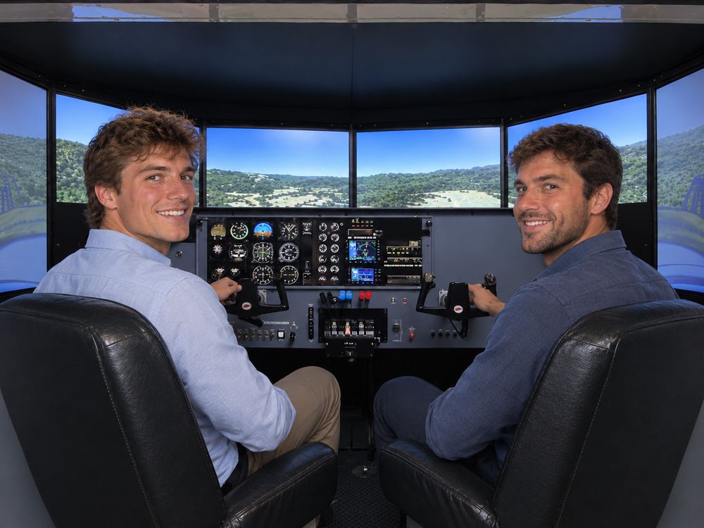 two smiling pilots practicing in the Redbird BE76 multi-engine flight simulator